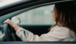 woman in gray hoodie sitting inside car during daytime