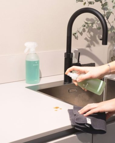 a woman is cleaning a kitchen sink with a rag