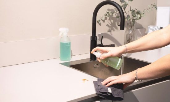 a woman is cleaning a kitchen sink with a rag