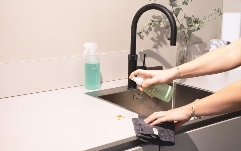 a woman is cleaning a kitchen sink with a rag