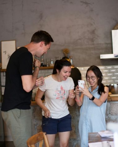 woman wearing white crew-neck shirt looking at smartphone friends