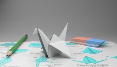 Handen die een origamikraan vouwen van wit papier op een houten tafel