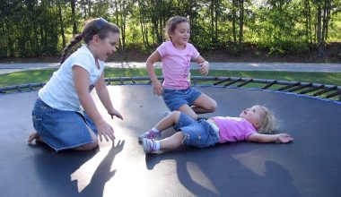 Kinderen springen op een trampoline in een tuin omgeven door groen